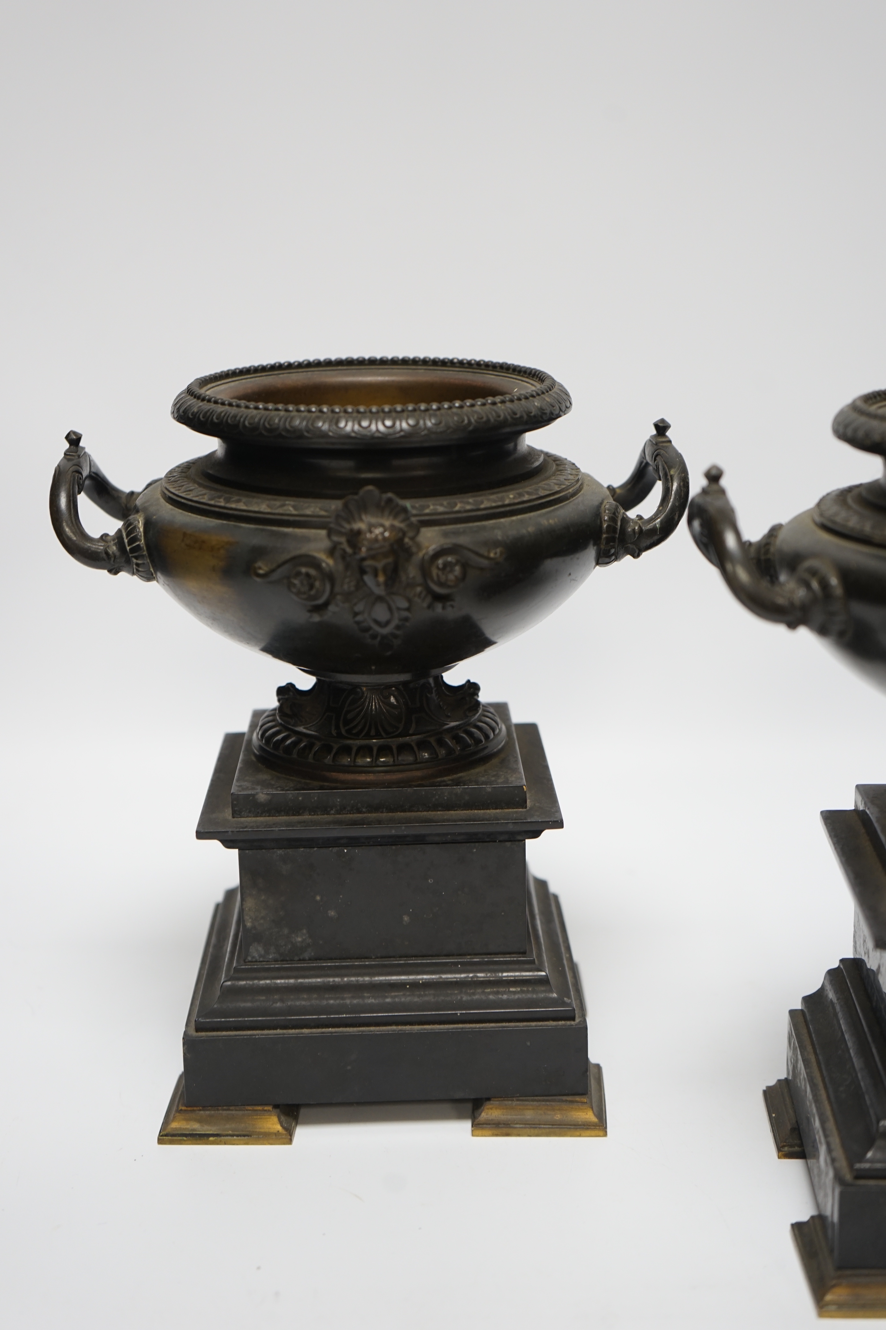 A pair of 19th century bronze urns on slate pedestals, 21.5cm high